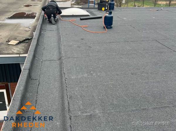 Dakdekker repareert bitumen dakbedekking op groot plat dak in Rheden