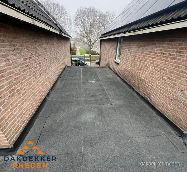 Plat dak met bitumen dakbedekking tussen bakstenen muren in Rheden Plat dak met bitumen dakbedekking tussen bakstenen muren in Rheden