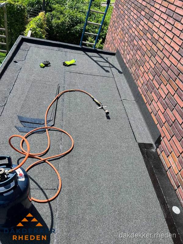 Plat dak met bitumen en brandgereedschap van dakdekkersbedrijf in Rheden