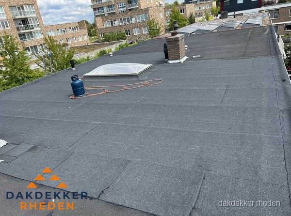 Bitumen dakbedekking op plat dak met lichtkoepel en schoorsteen in Rheden