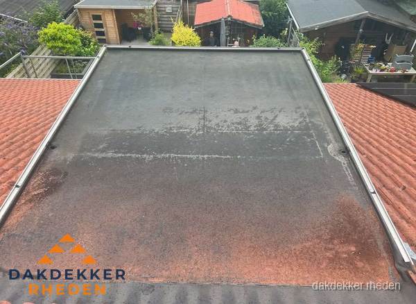 Verouderd plat dak met slijtage tussen schuine daken in Rheden Verouderd plat dak met slijtage tussen schuine daken in Rheden