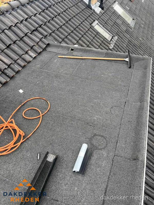 Plat dak reparatie met gereedschap en loodstroken in Rheden