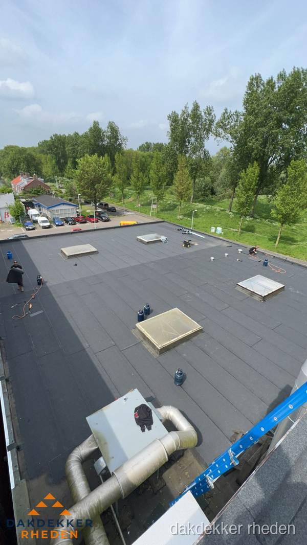Dakdekker aan het werk op groot plat dak met bitumen in Rheden